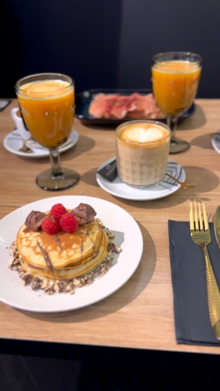 Desayuno con tortitas, frutos rojos, café y zumos de naranja